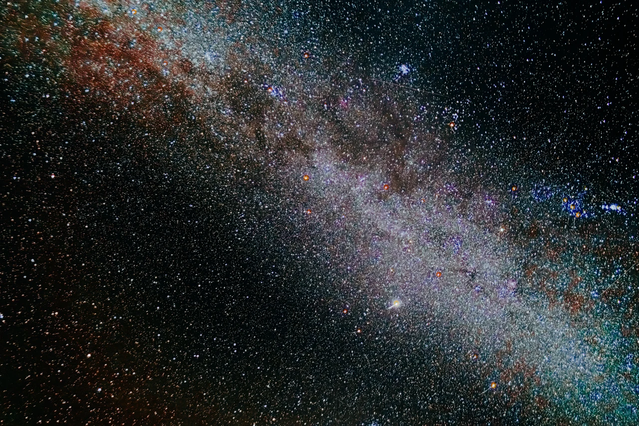 A dense star field and dark dust clouds across the Milky Way.